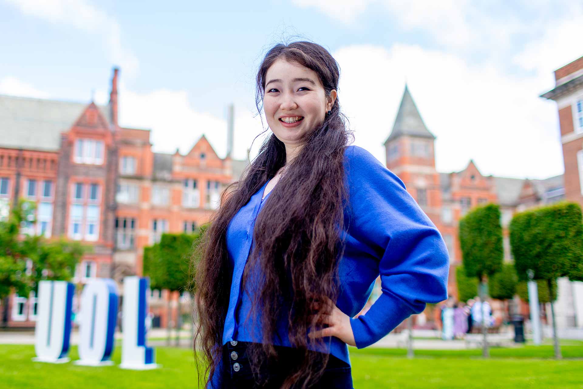 A international postgraduate researcher in a grassy courtyard on campus.
