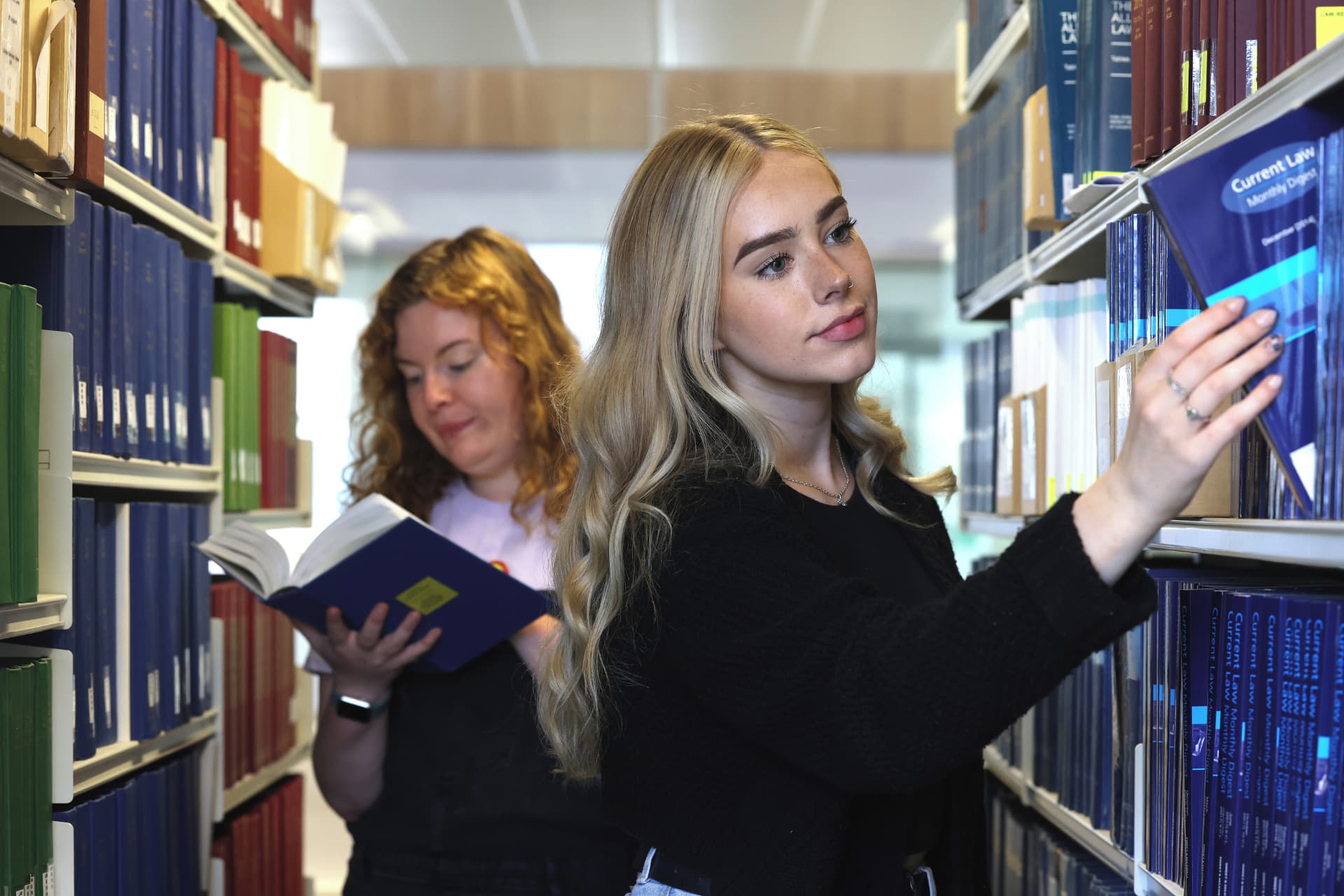 Two students looking through book shelves engaging with the books.